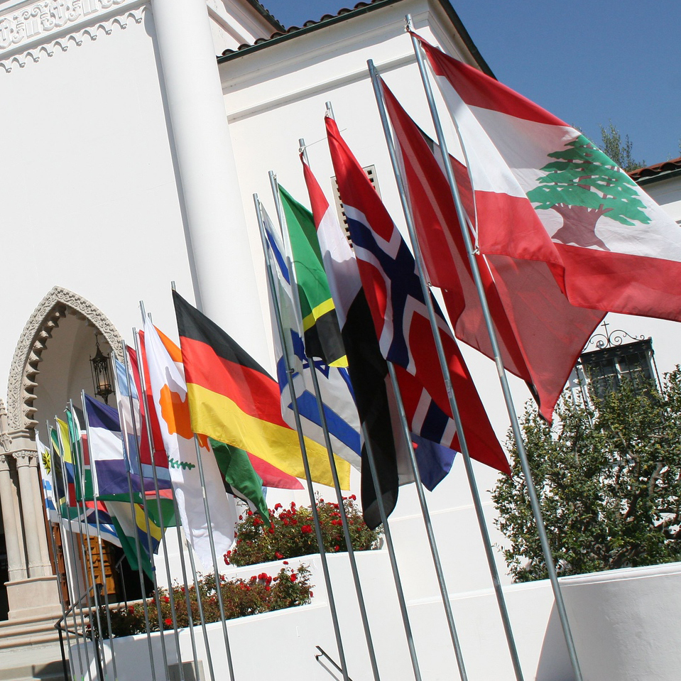 Approximately 15 international flags on poles in front of Sacred Heart Chapel.